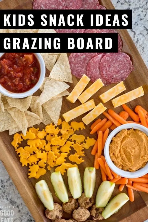 wooden tray with meat, cheese, chips, salsa, and apple slices