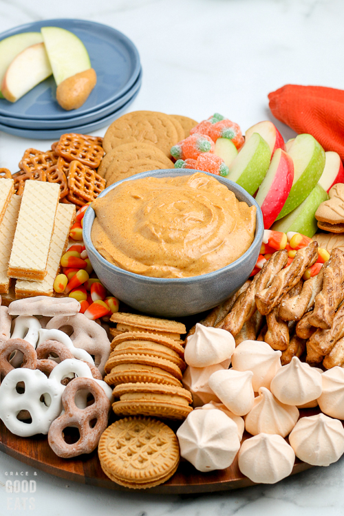 bowl of pumpkin dip surrounded by cookies and apple slices