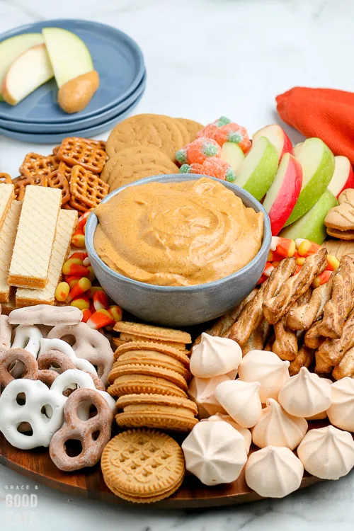 bowl of pumpkin dip surrounded by cookies and apple slices