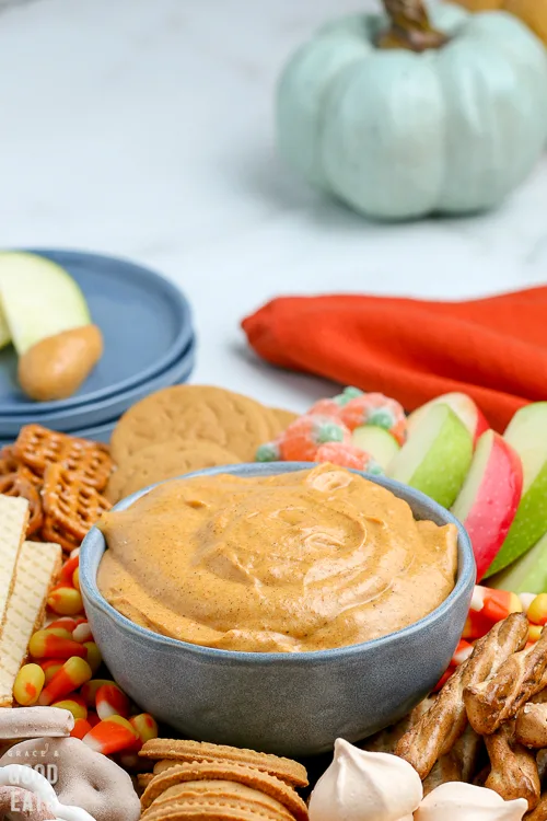 pumpkin dip in a blue bowl with pumpkins in the background