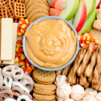 bowl of pumpkin dip surrounded by cookies and apple slices