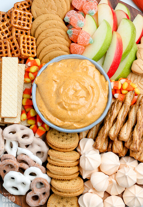 bowl of pumpkin dip surrounded by cookies and apple slices