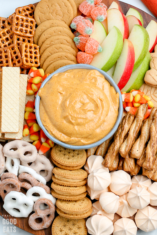 bowl of pumpkin dip surrounded by cookies and apple slices