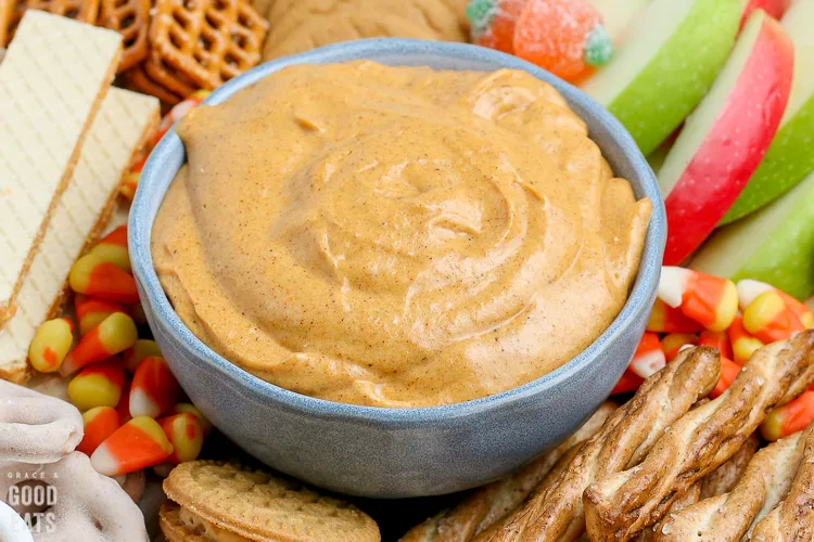 bowl of pumpkin dip surrounded by cookies and apple slices
