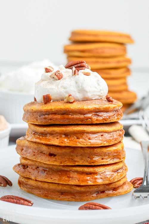 pumpkin pancakes stacked on a plate with more in the background