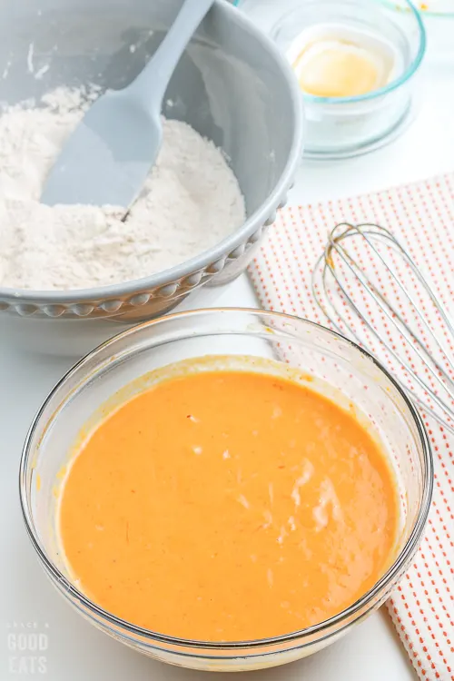 pumpkin pancake batter in a glass bowl next to a whisk