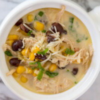 green chile chicken soup with corn and black beans in a white crock