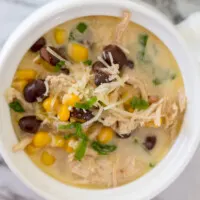 green chile chicken soup with corn and black beans in a white crock