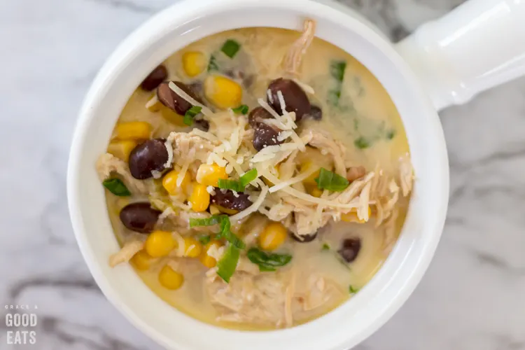 green chile chicken soup with corn and black beans in a white crock