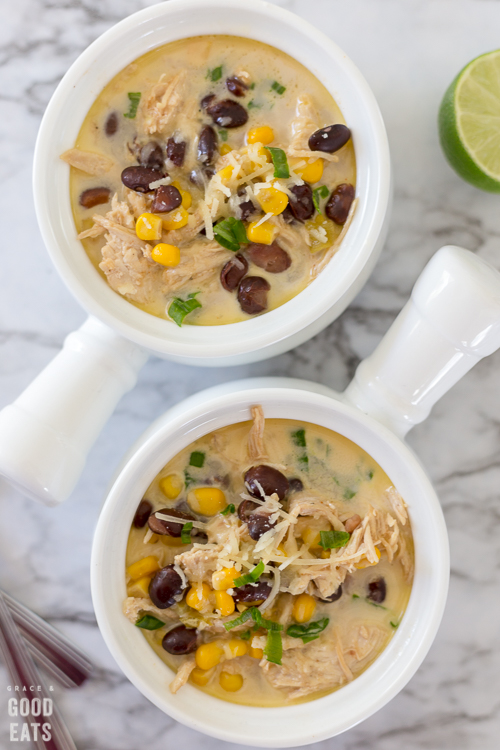 green chile chicken soup in a white bowl next to another bowl of soup