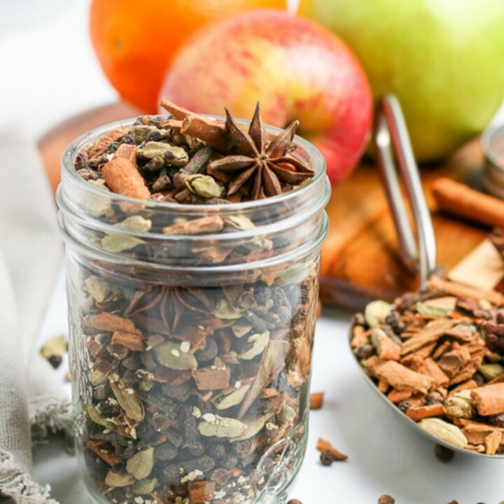 jar of mulling spices next to mulled cider and fruit