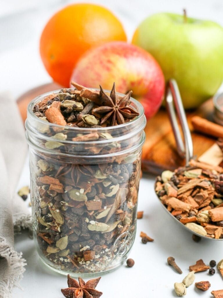 jar of mulling spices next to mulled cider and fruit