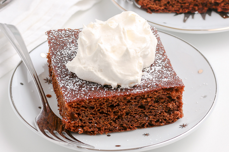 white plate with silver stars and a slice of gingerbread cake