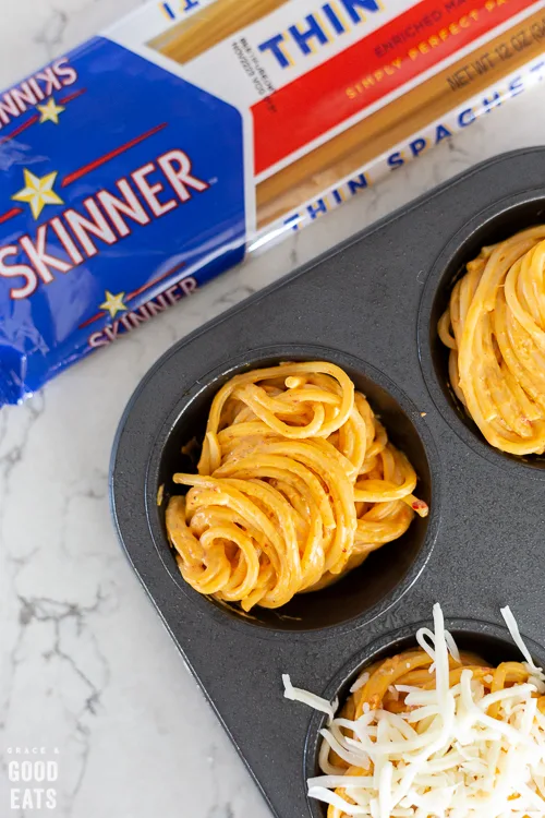 spaghetti in a muffin tin next to a package of Skinner pasta