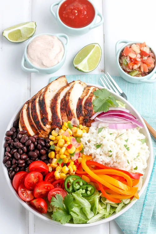 chicken burrito bowl in a white plate next to a blue linen