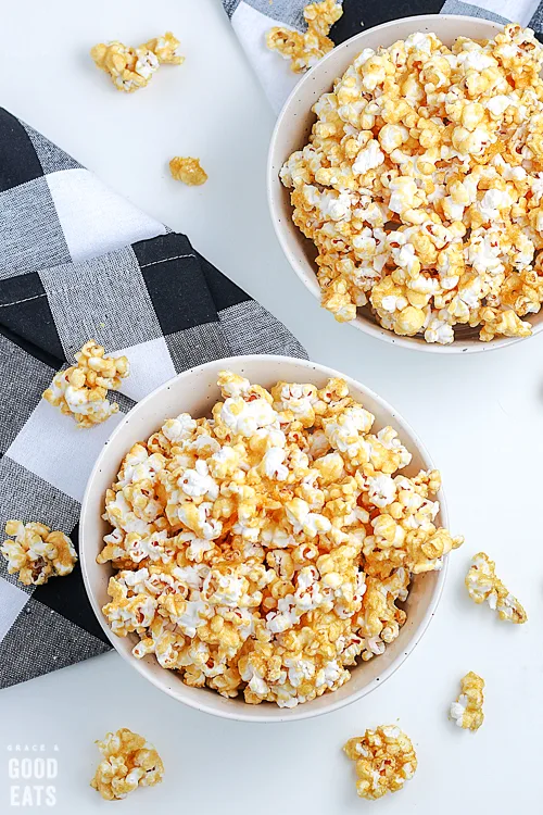 white bowl of caramel popcorn next to a checkered napkin