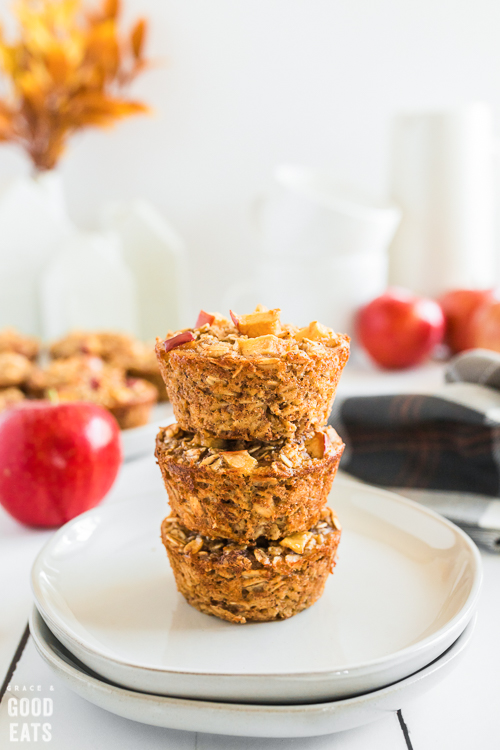 stack of three cinnamon apple oatmeal cups on a plate with apples in the background