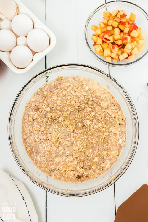 bowl of old-fashioned oats next to a bowl of eggs and diced apples